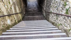 Degraus de pedra com listras brancas, conduzindo a um nível mais alto.
