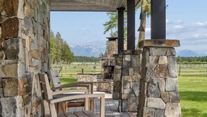 Ein Steinkamin mit Blick auf die Berge, Sitzmöglichkeiten im Freien und eine überdachte Terrasse.