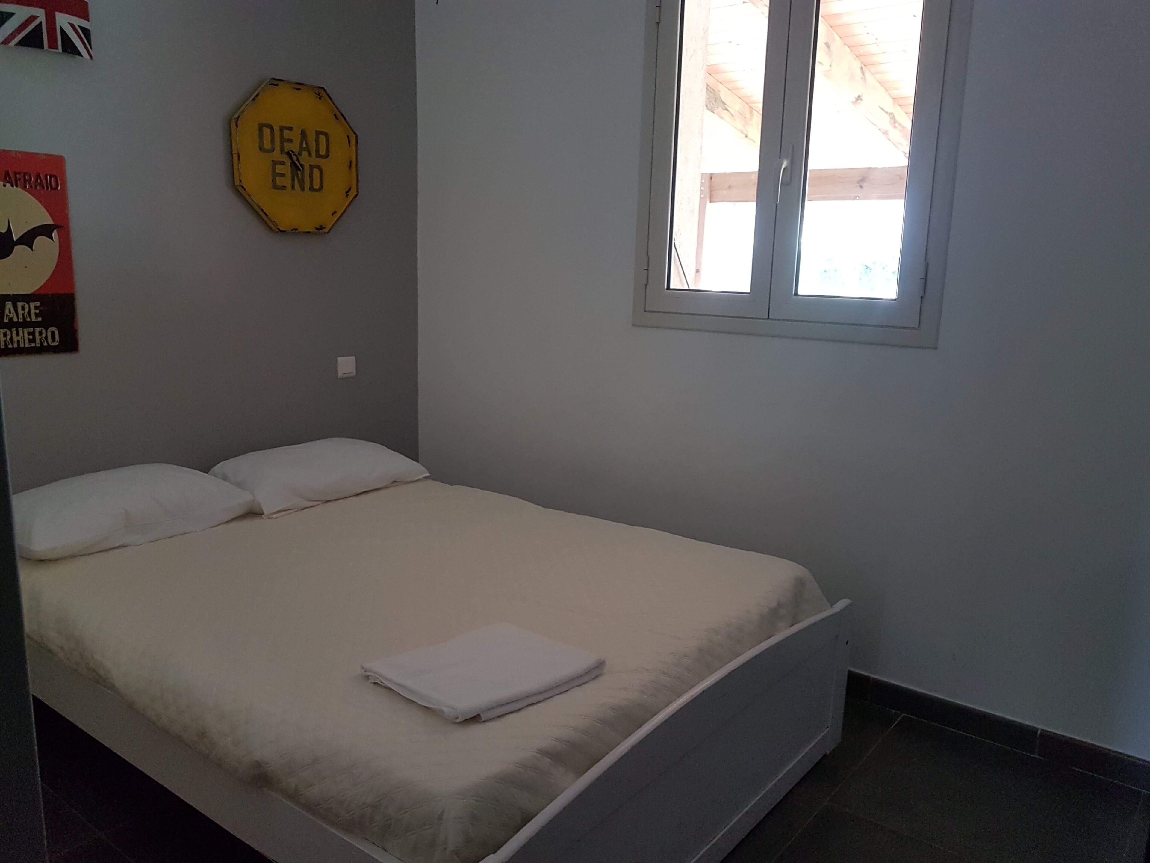 A bedroom with a bed, a window, a 'DEAD END' sign, and a poster on the wall.