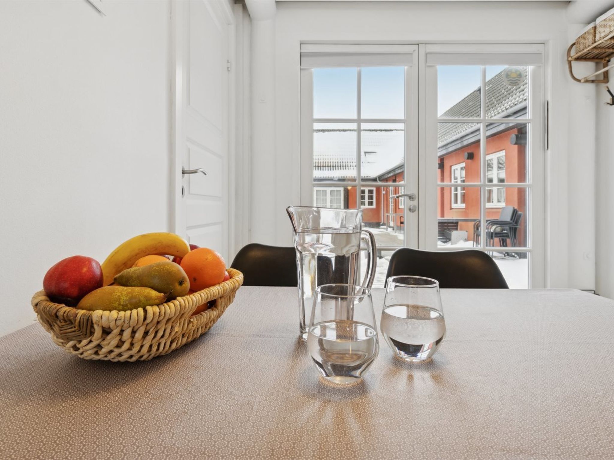 Ett matbord med en fruktskål, en kanna och två glas.
