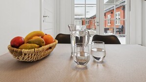 Ett matbord med en fruktskål, en kanna och två glas.