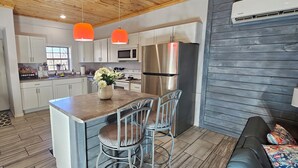 A modern kitchen with white cabinets, a stainless steel refrigerator, and a wooden island with bar stools.