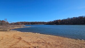A river with a pebbly shore and trees in the background.