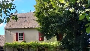 Une maison à deux étages avec un toit en briques, des volets rouges et une clôture en bois.