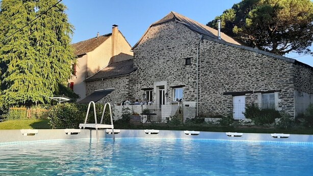Un bâtiment en pierre avec une piscine devant.