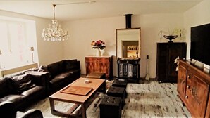 Un salon comprenant un canapé, une table basse, un meuble en bois, un téléviseur et un lustre.