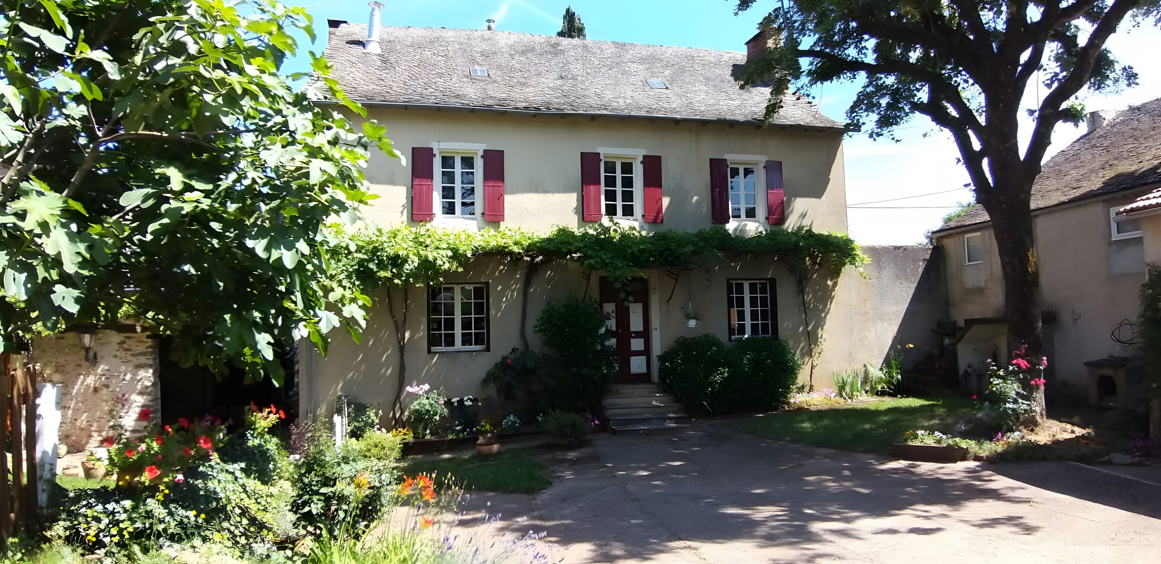 A two-story house with a garden entrance, a stone wall, and a pathway leading to the door.