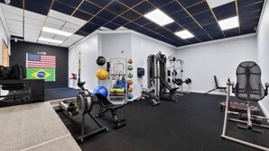 A gym with exercise equipment, a desk, and flags on the wall.