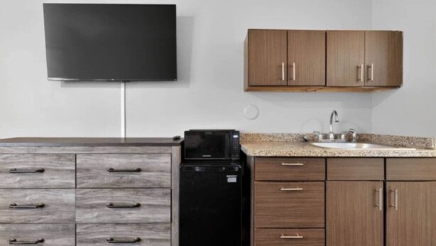 A kitchen with a microwave, a sink, and wooden cabinets.