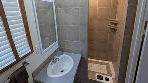 Un baño con lavabo, espejo y zona de ducha.