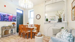 Een woonkamer met een eethoek, een televisie, een klok en een open haard.