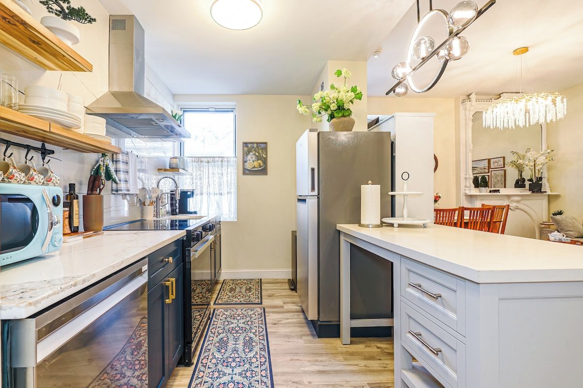 A modern kitchen with a central island, built-in appliances, and a decorative chandelier.