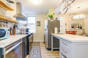 Een moderne keuken met een centraal eiland, inbouwapparatuur en een decoratieve kroonluchter.