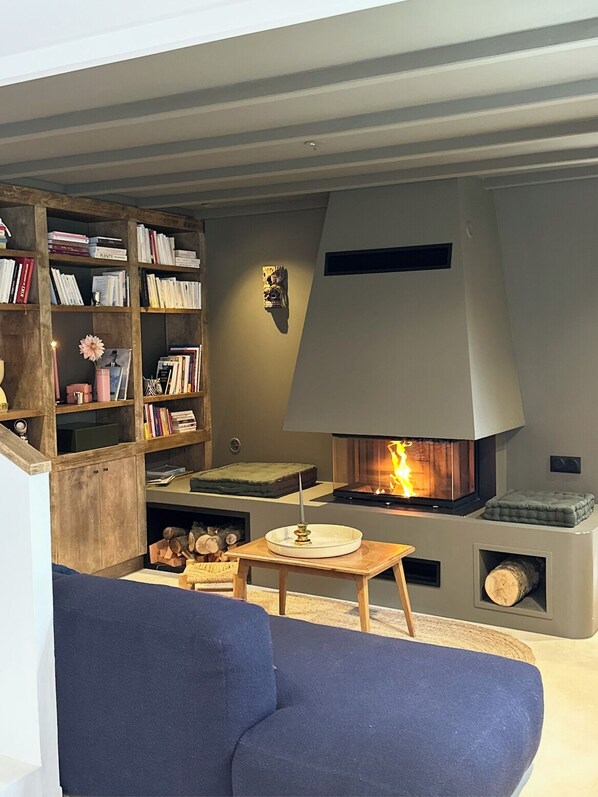 A cozy living room with a fireplace, a bookshelf, and a blue sofa.