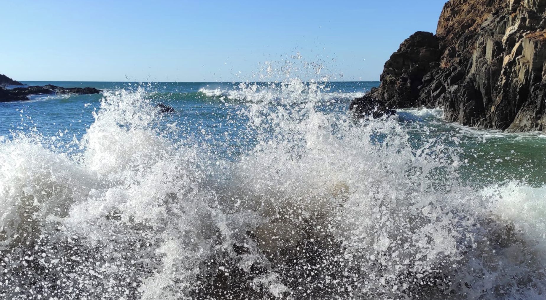 A rocky coastline with waves crashing against the shore.