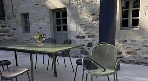 An outdoor dining area with a stone wall, a table, and chairs.