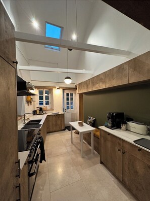 A modern kitchen with a central island, a built-in oven, and a dining area with a table.