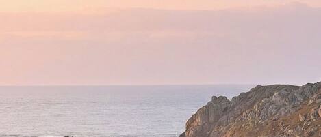 Una proprietà costiera con una casa vicino al mare, terreno roccioso e cielo sereno.