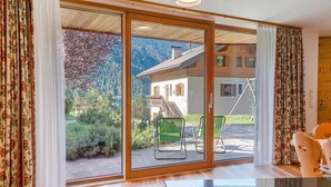 A room with a sliding glass door leading to an outdoor patio with chairs and a table. - Chalet 'Petrunderhof Sommertraum' with Mountain View, Shared Terrace and Wi-Fi (Villnöß)