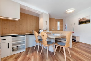 Una cocina moderna con armarios de madera, una mesa de comedor con sillas y una cruz en la pared.