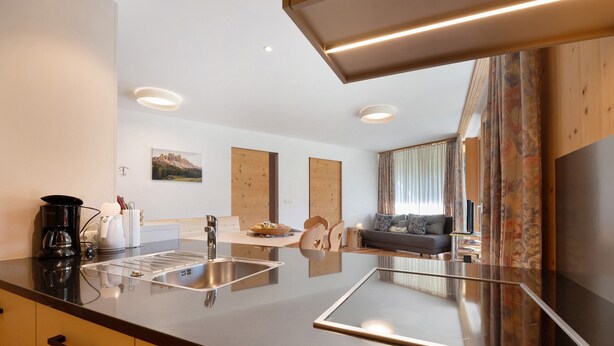 Eine moderne Küche mit Kochinsel, ein Essbereich mit einer Couch und ein Wohnzimmer mit einem Sofa.