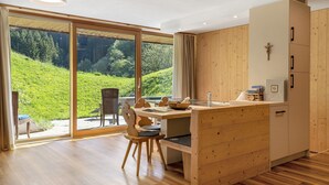 Een moderne keuken met houten keukenkastjes, een eethoek met tafel en stoelen, en een grote schuifdeur naar een tuin.