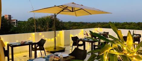 An outdoor dining area with tables, chairs, and string lights.