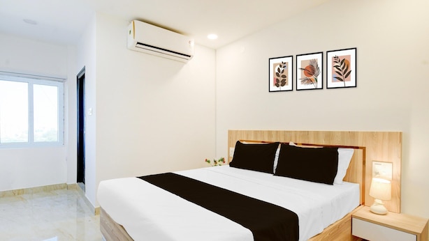 A modern hotel room with a large bed, a bedside table with a lamp, and a window with a view. - Saver Single Karmanghat Midtown (Hyderabad)