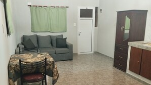 Una habitación con cama, una mesa con sillas, un sofá, un armario y una puerta.