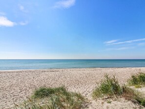 Una playa arenosa con cielo azul despejado y mar tranquilo.