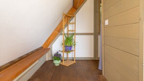 A wooden staircase with a wooden ladder, a green potted plant, and a blue potted plant.