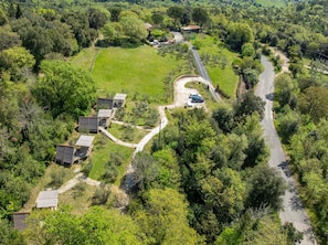 Vista aérea de una propiedad rural con varias cabañas de madera, un camino sinuoso y vegetación circundante.
