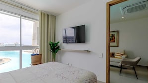 Una camera d'albergo con un letto, una TV a parete, vista mare e una sedia.