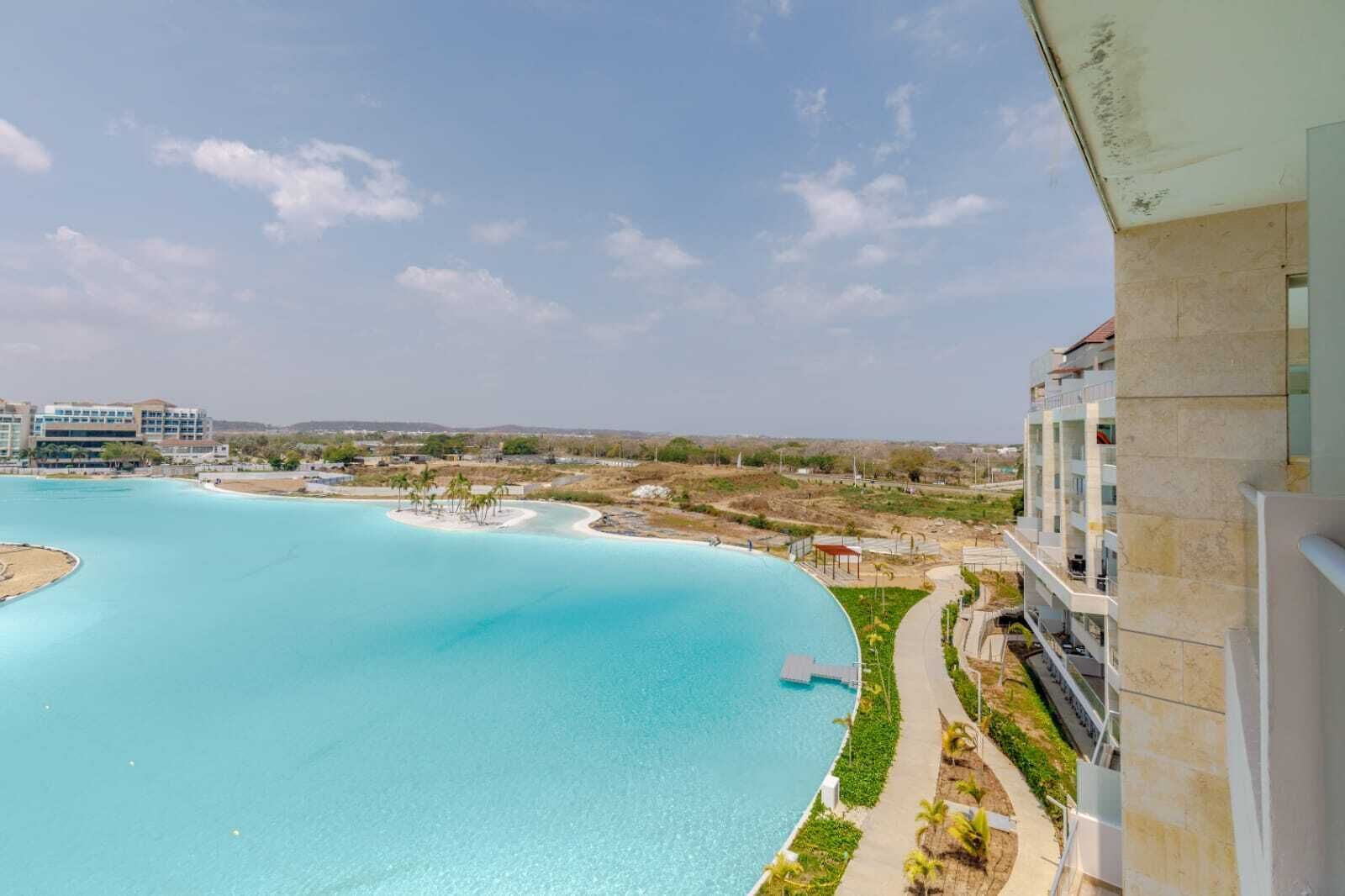 Ein Resort mit einem großen Pool, einer kleinen Insel und Blick auf entfernte Gebäude.