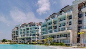 Un hotel fronte spiaggia con numerosi balconi, una piscina e una spiaggia sabbiosa.
