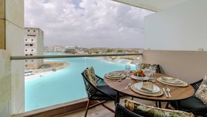 Un balcone con un tavolo da pranzo per due, vista su uno specchio d'acqua e degli edifici.