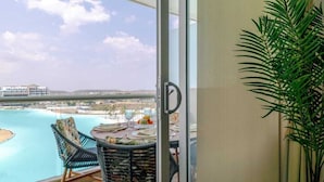 Un balcone con vista sulla spiaggia e sull'oceano, un tavolo da pranzo con sedie e una pianta in vaso.