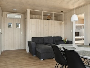 A modern interior with a grey sectional sofa, a dining table with black chairs, and a white pendant light. - "Eleni" - 3m from the sea by Interhome (Slagelse)