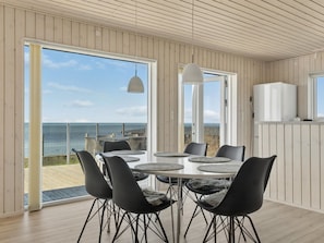 A modern dining area with a view of the sea, featuring a round table, black chairs, and a pendant light. - "Eleni" - 3m from the sea by Interhome (Slagelse)