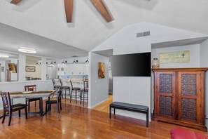 A spacious living area with a dining table, chairs, a bench, a TV, and a cabinet. - Upscale Quiet Close to everything (Palm Harbor)