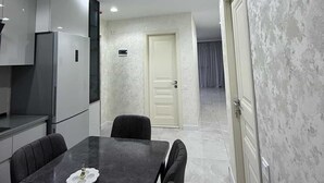 Cozinha moderna com área de jantar, uma porta branca e corredor que dá para outro quarto.