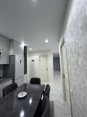 Una cocina moderna con comedor, una puerta blanca y un pasillo que conduce a otra habitación.