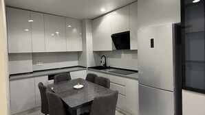 Uma cozinha moderna com uma mesa de jantar, cadeiras e uma geladeira.