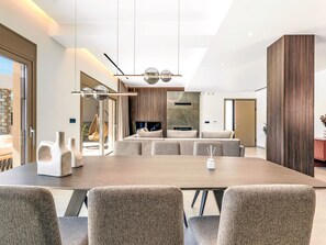 Un comedor moderno con una mesa larga, varias sillas y una lámpara colgante.