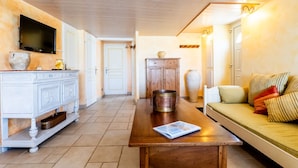 Una sala de estar con una mesa de madera, un sofá, un televisor y un mueble.