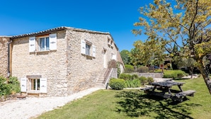 Un edificio de piedra con una ventana pequeña, una mesa de picnic y un césped bien cuidado.