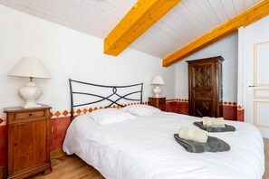 Een slaapkamer met een bed, een houten garderobe en twee bedlampjes.