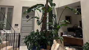 A multi-level interior with a staircase, a large potted plant, and a desk with a computer.