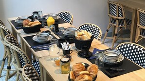 A dining table set with plates, glasses, a pitcher, a basket of bread, and a jar of honey.