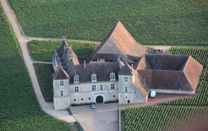 An aerial view of a large estate with a prominent central building, surrounded by expansive green fields. - DOUCE NUITS (Nuits-Saint-Georges)